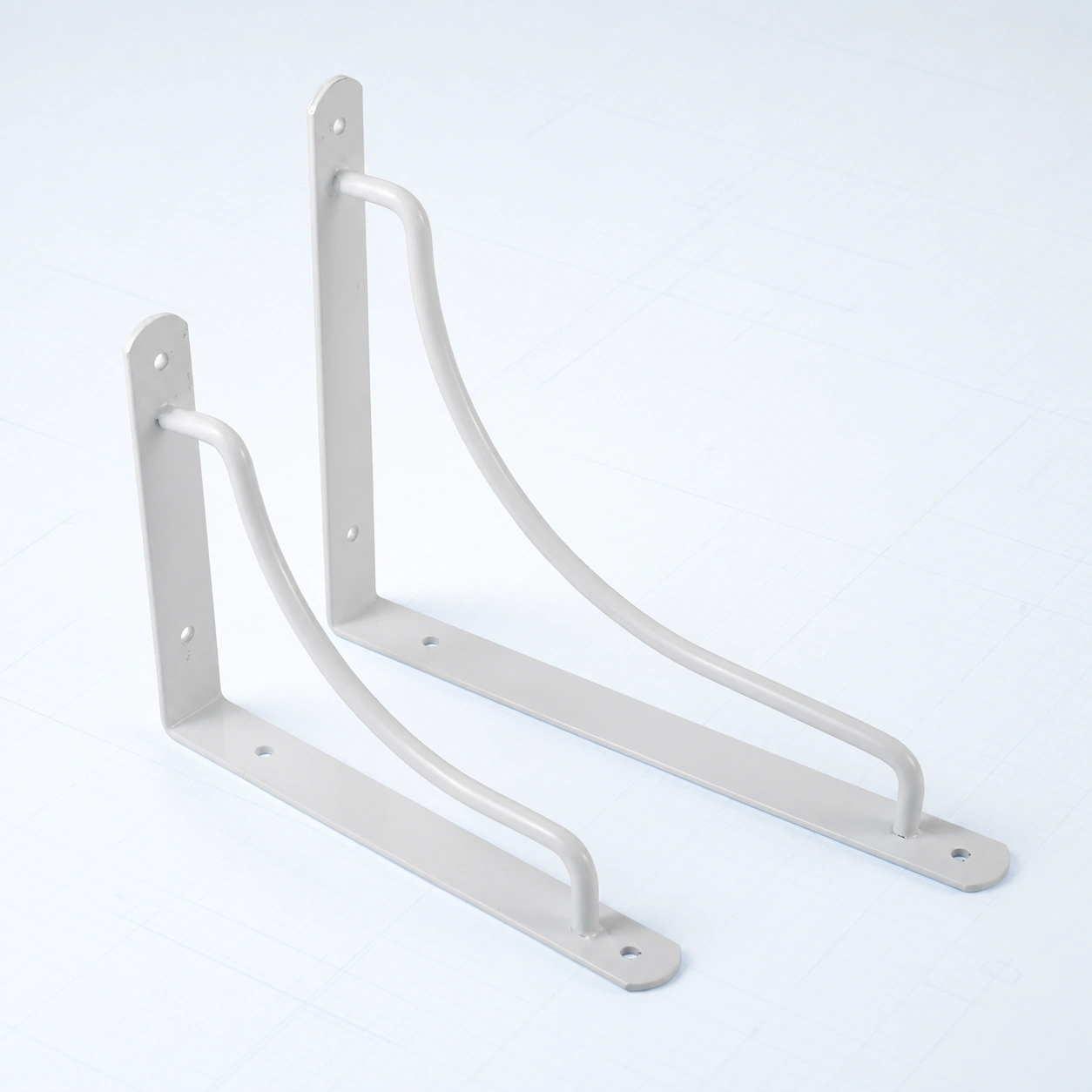 Curved decorative metal shelf bracket on a pale ice-blue studio background